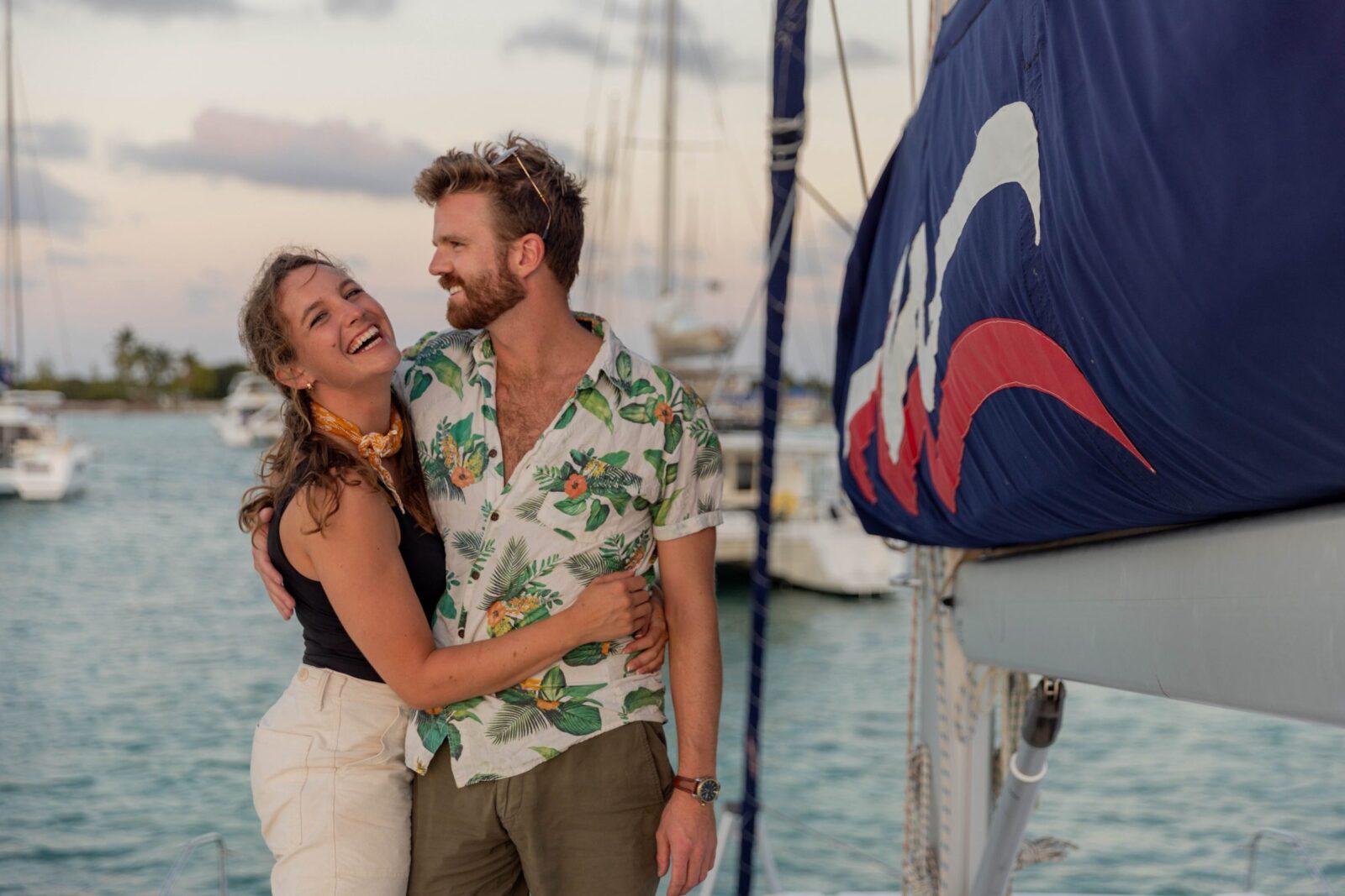 A couple at Starchaser’s bow at sunset with the sail up