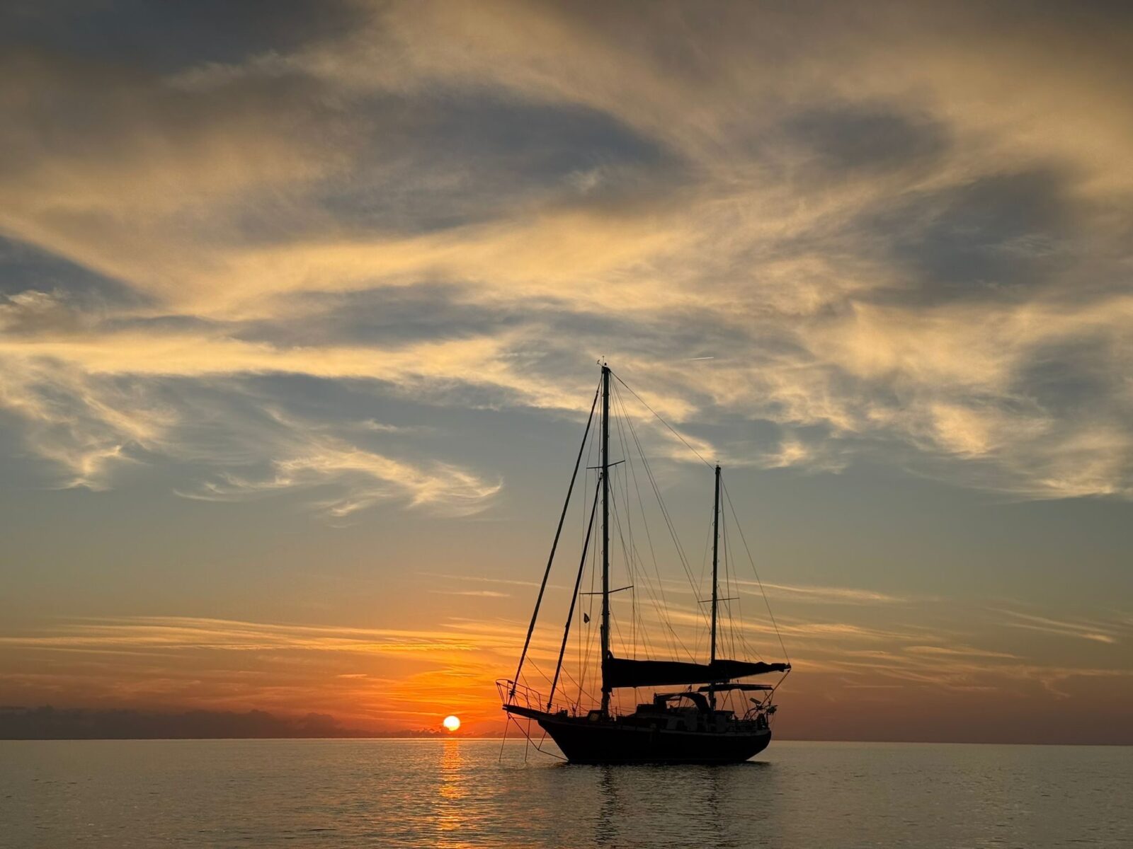 Starchaser at anchor at sunset, both masts against a gold sky